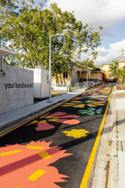 Image shows completed artwork New Bloom on the pavement surface for the converted Tarlina Lane shared zone. The artwork is a vibrant, scattered botanic garland, forming an imaginative hybrid garden.