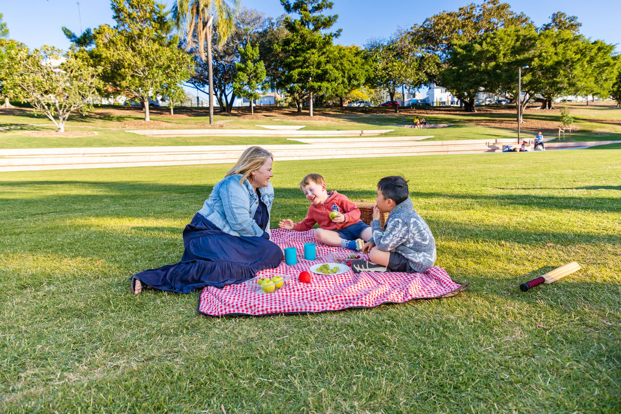 A woman with 2 kids having a picnic at Spring Hill Common, Victoria Park.