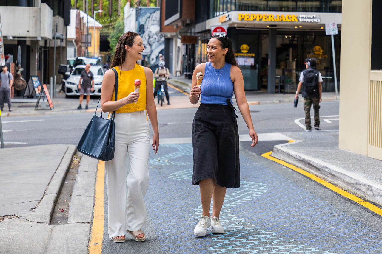 2 young women with ice-creams walking through Fish Lane.