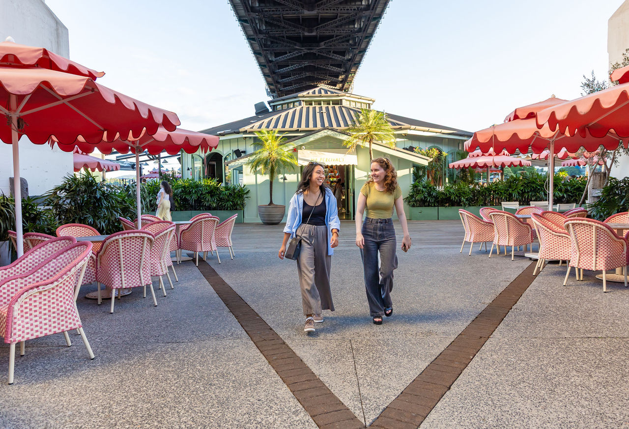 Two young women walking in front of Mr Percival's at Howard Smith Wharves.
