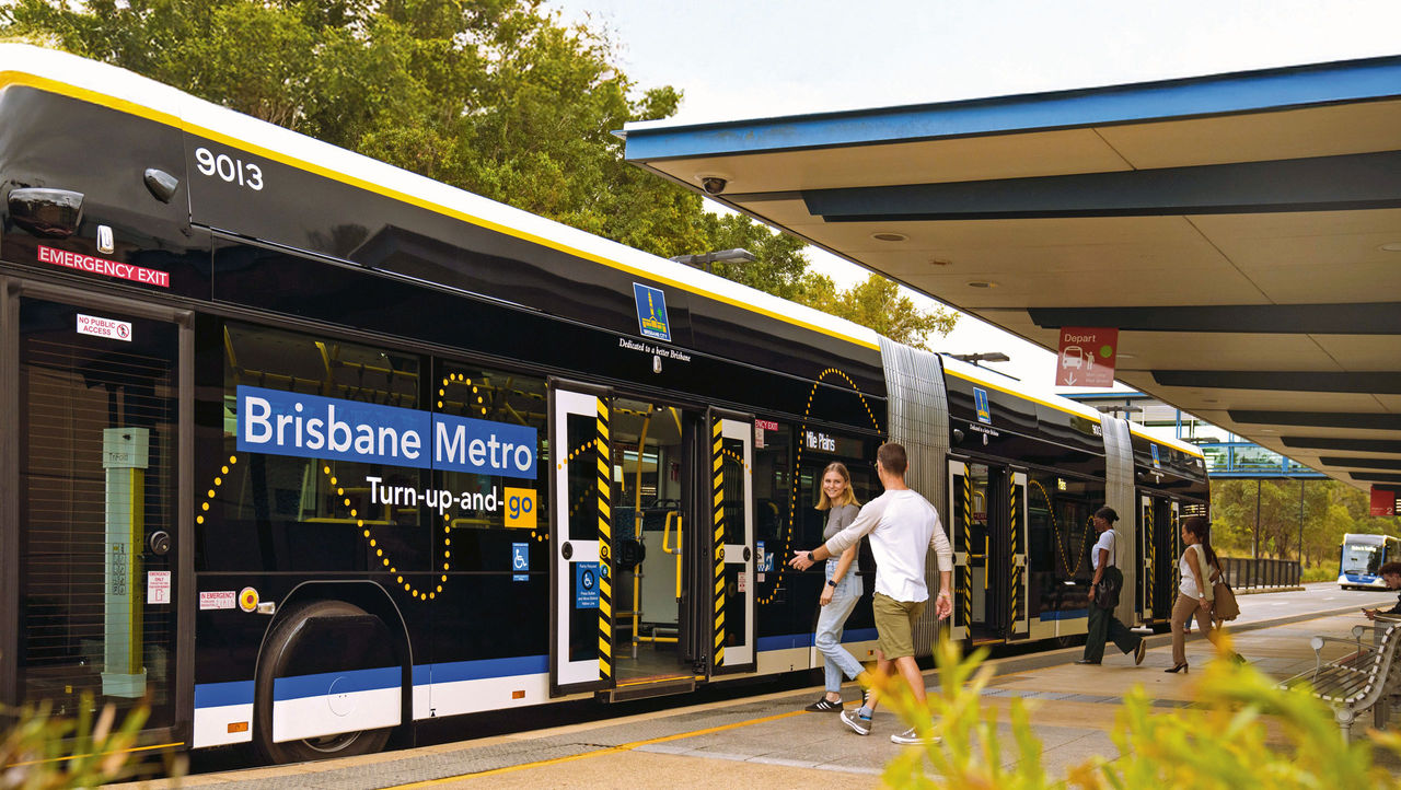 Passengers boarding a Brisbane Metro vehiicle at a bus station platform