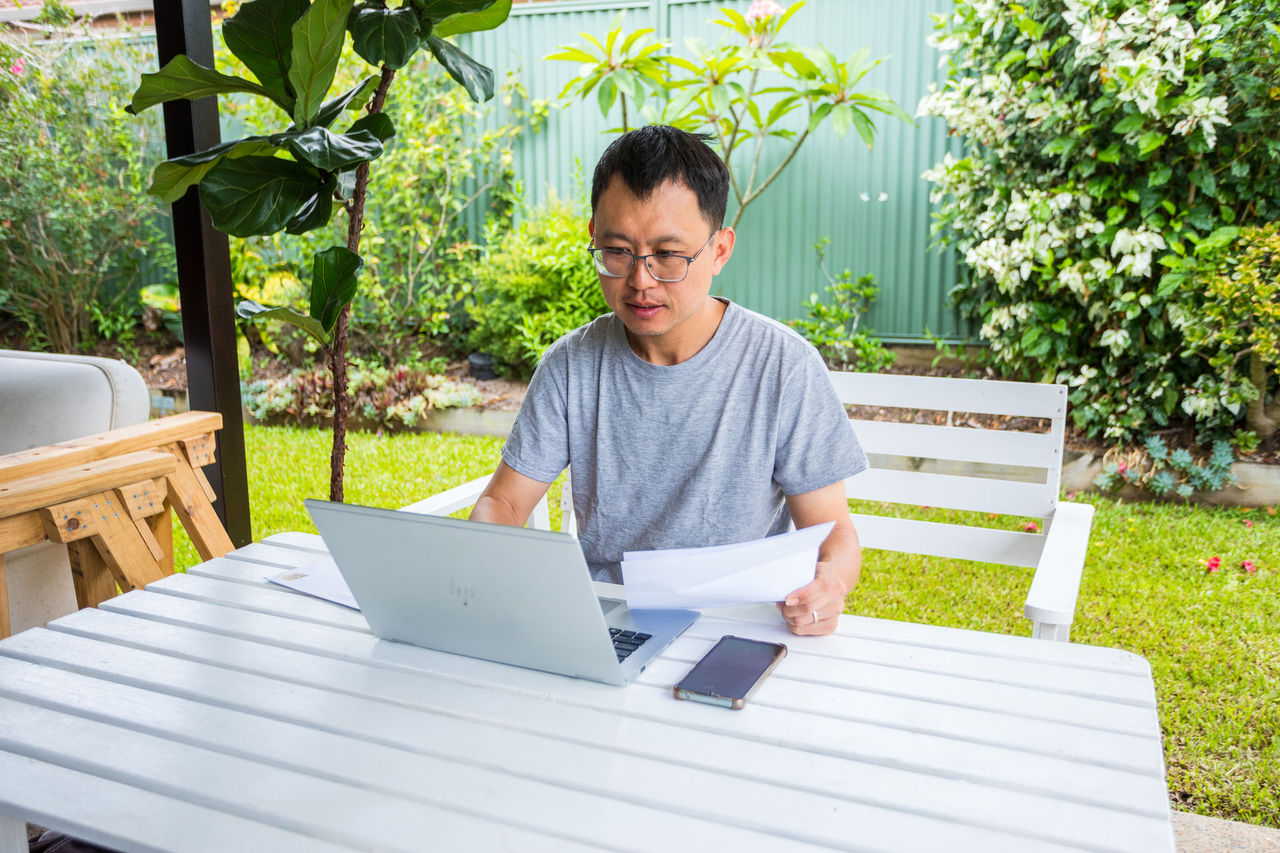 Man sitting at an outdoor table in front of a laptop paying a bill.