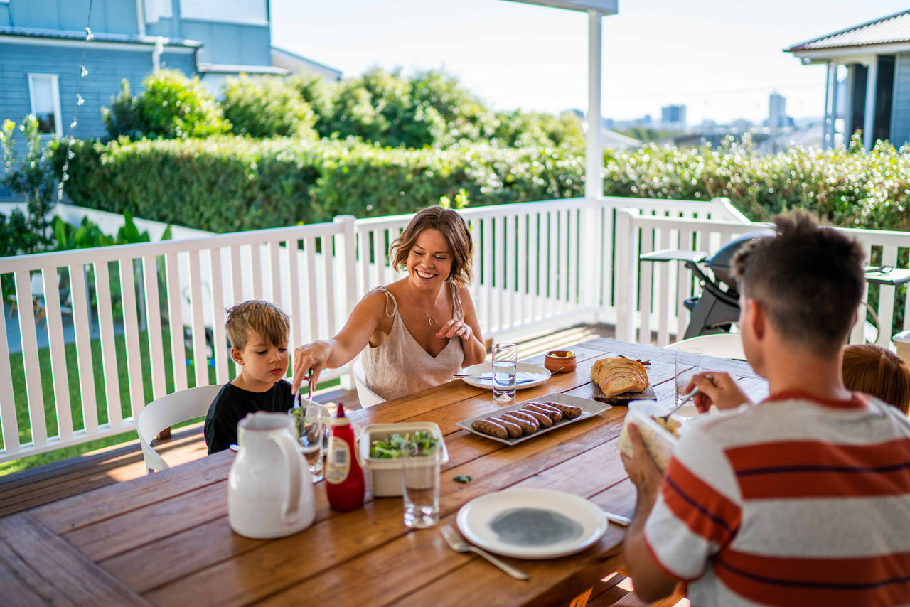 Family on a back deck in Brisbane eating a barbecue lunch.