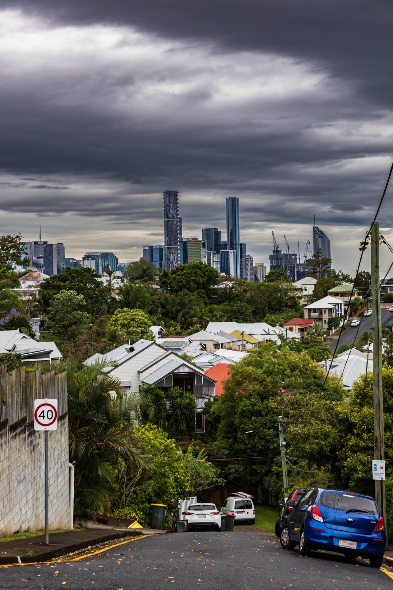 Dark grey storm clouds over the Brisbane City skyline viewed from the top of a Paddington street.
