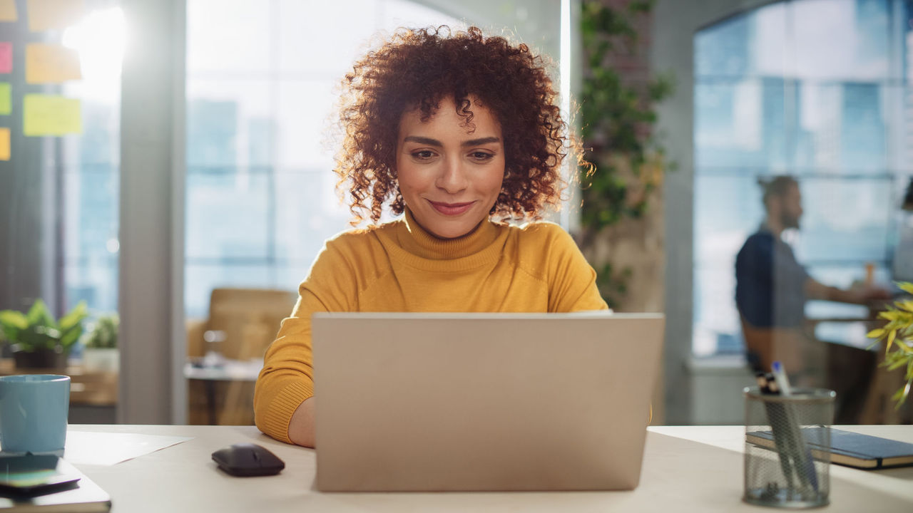 Young woman using a laptop in an office setting.