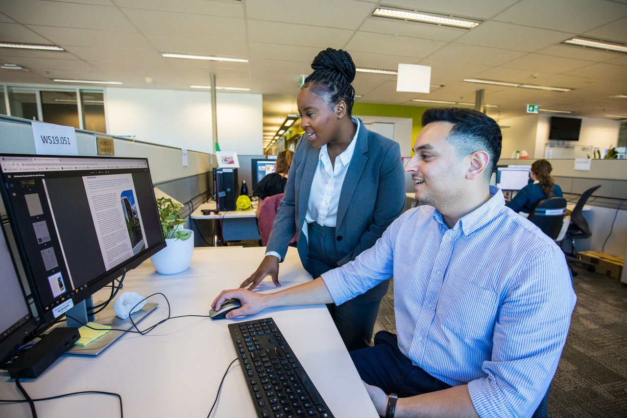 Two office-based employees looking at screen on a Council work station.