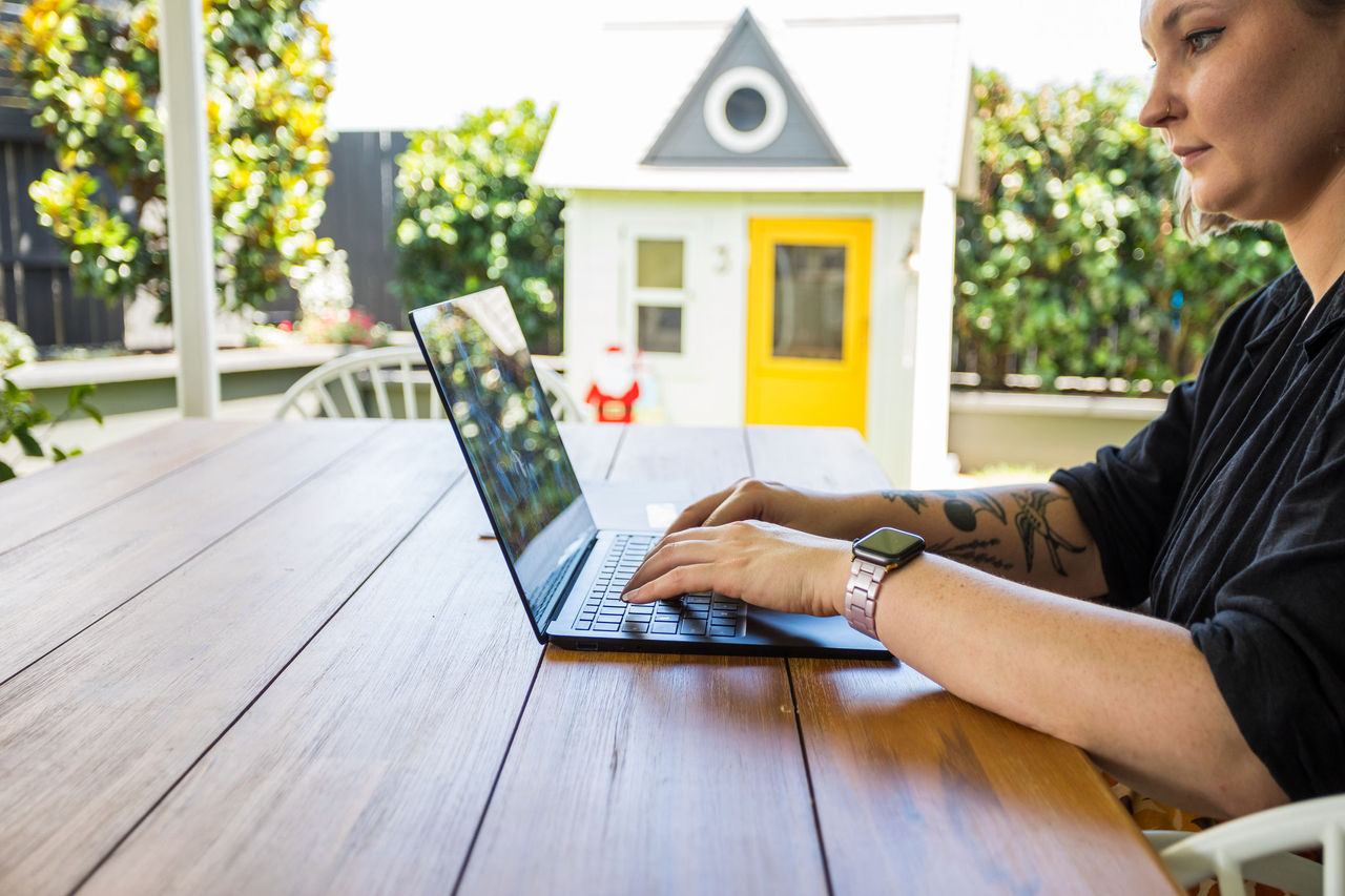 Wolan using a laptop at a covered outdoor table.