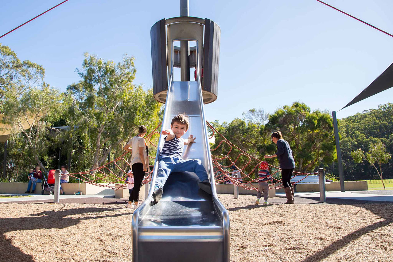 Young boy sliding on a slippery dip at Whites Hill Reserve playground.