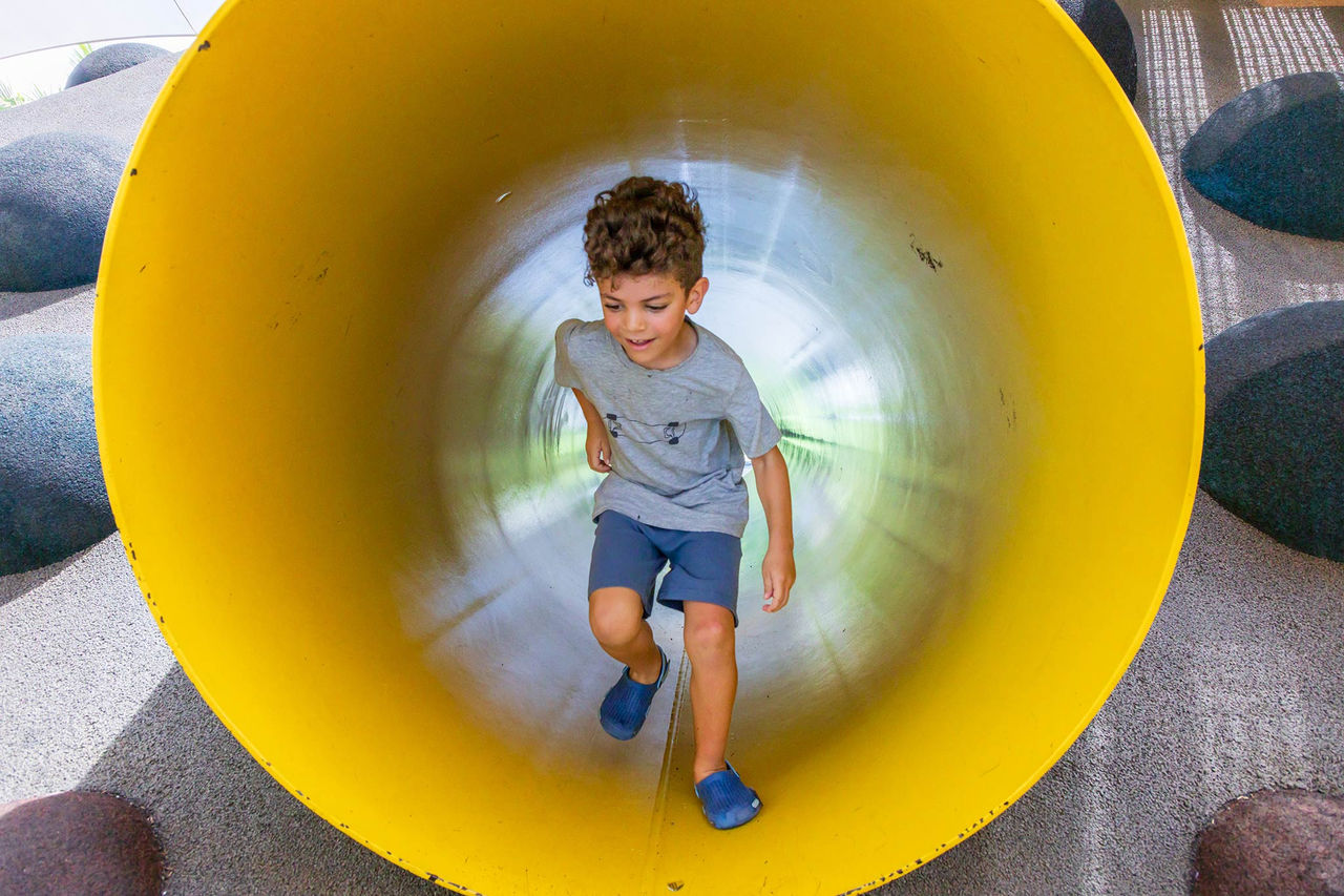 Young child running through play equipment in Hercules Street Park.