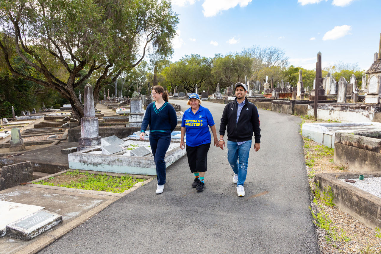 2 people walking with a female Brisbane Greeter in a historic Brisbane cemetery.