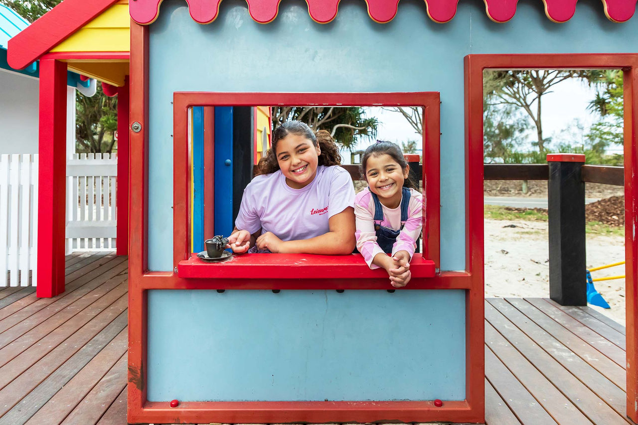 Two young girls in a house structure at the Wynnum Wading Pool Park playground.