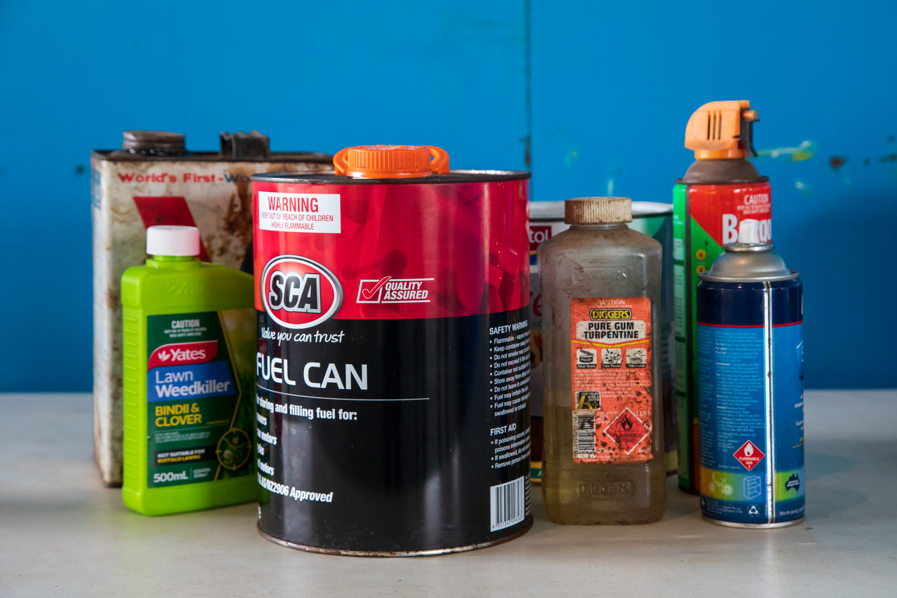 A range of household chemcials including a fuel can, lawn weed killer, oil, spray paint, insect spray, paint and turpentine.