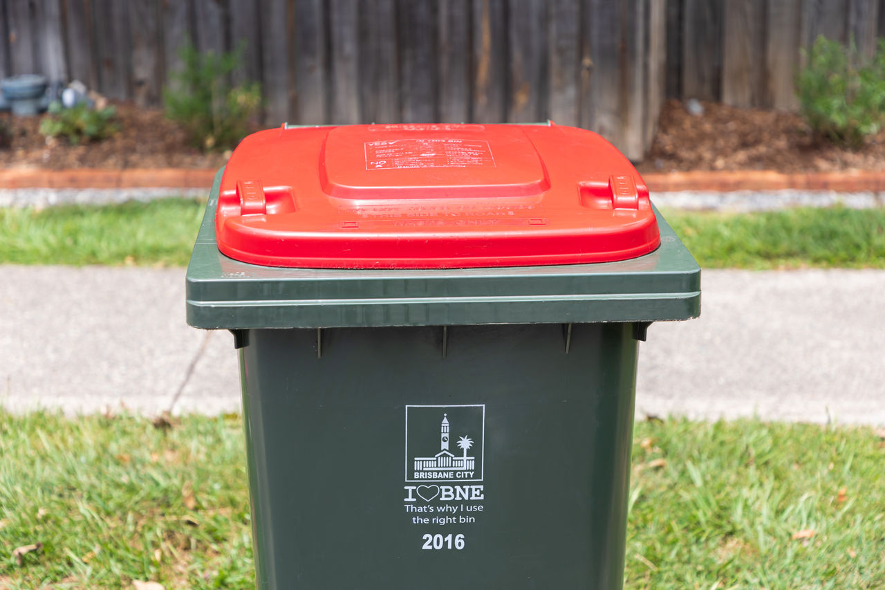 Red general waste bin on footpath.