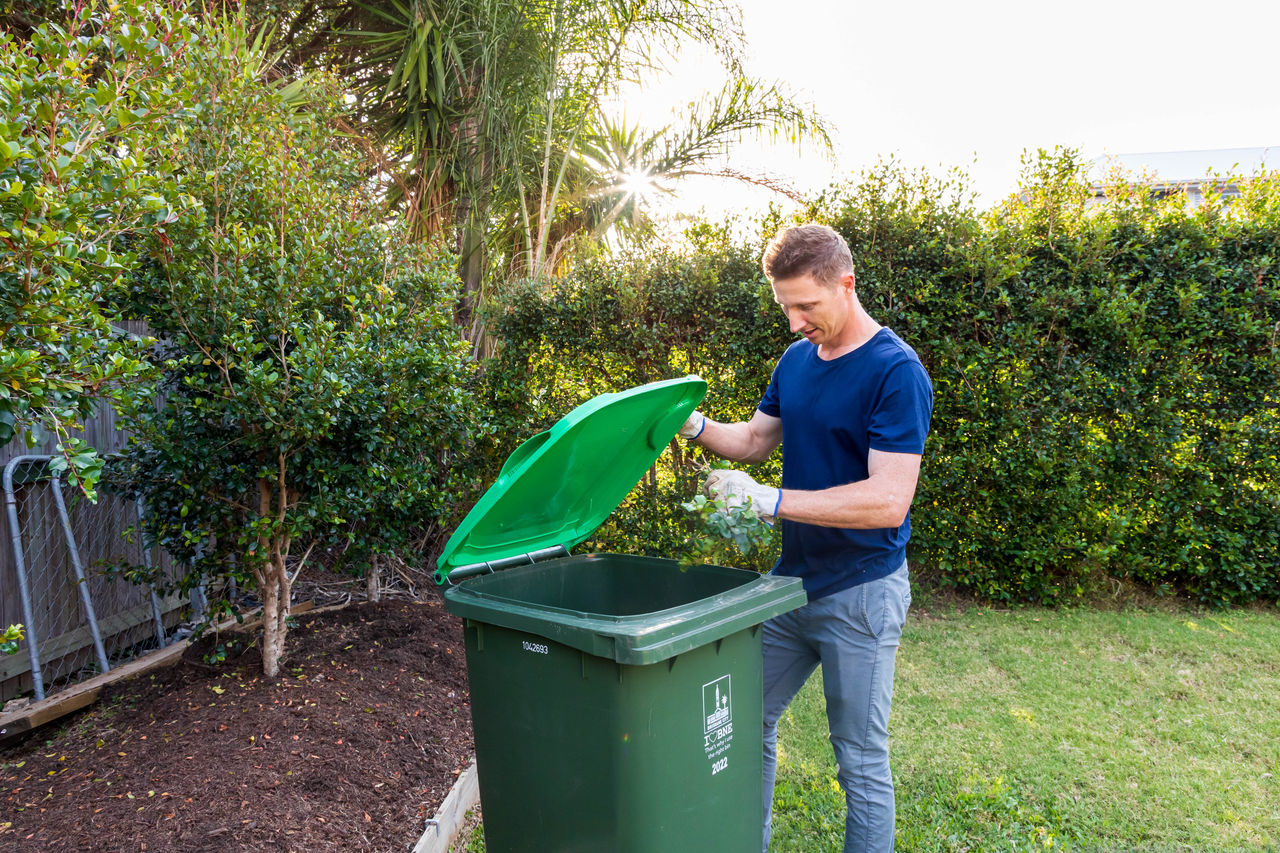 Man putting green waste in green bin.