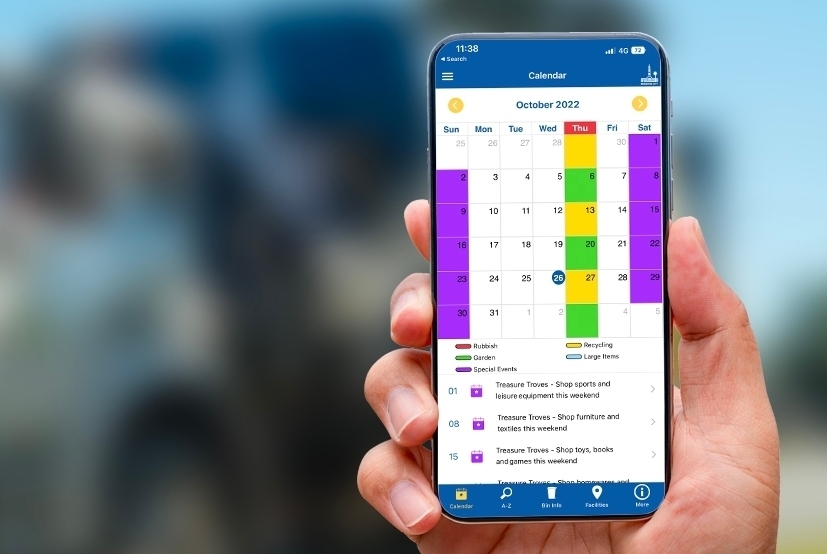 Hand holding smartphone displaying Council's Bin and Recycling app with bin collection calendar.