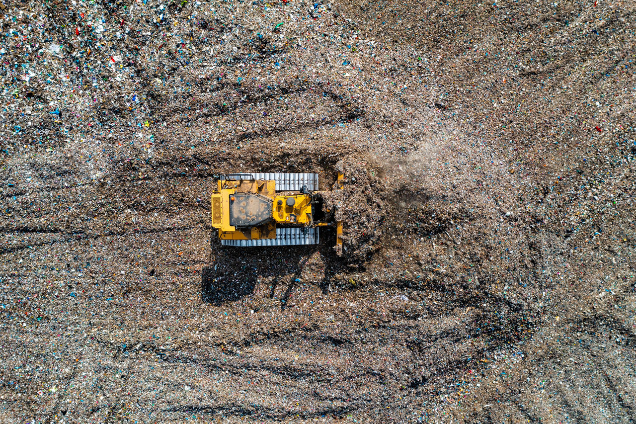 Industrial bulldozer moving waste on a large landfill site.