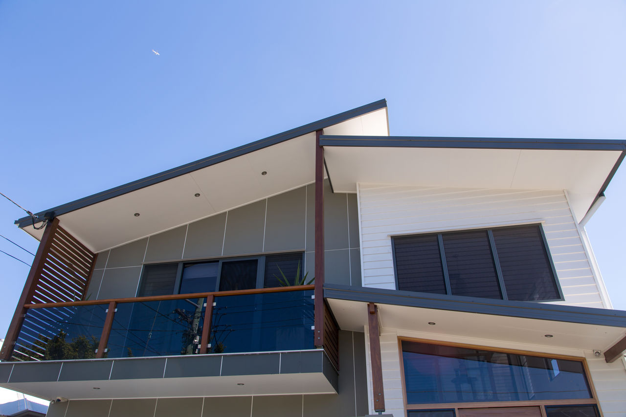 Second story of a new house featuring a roof, white and grey facades, and a balcony.