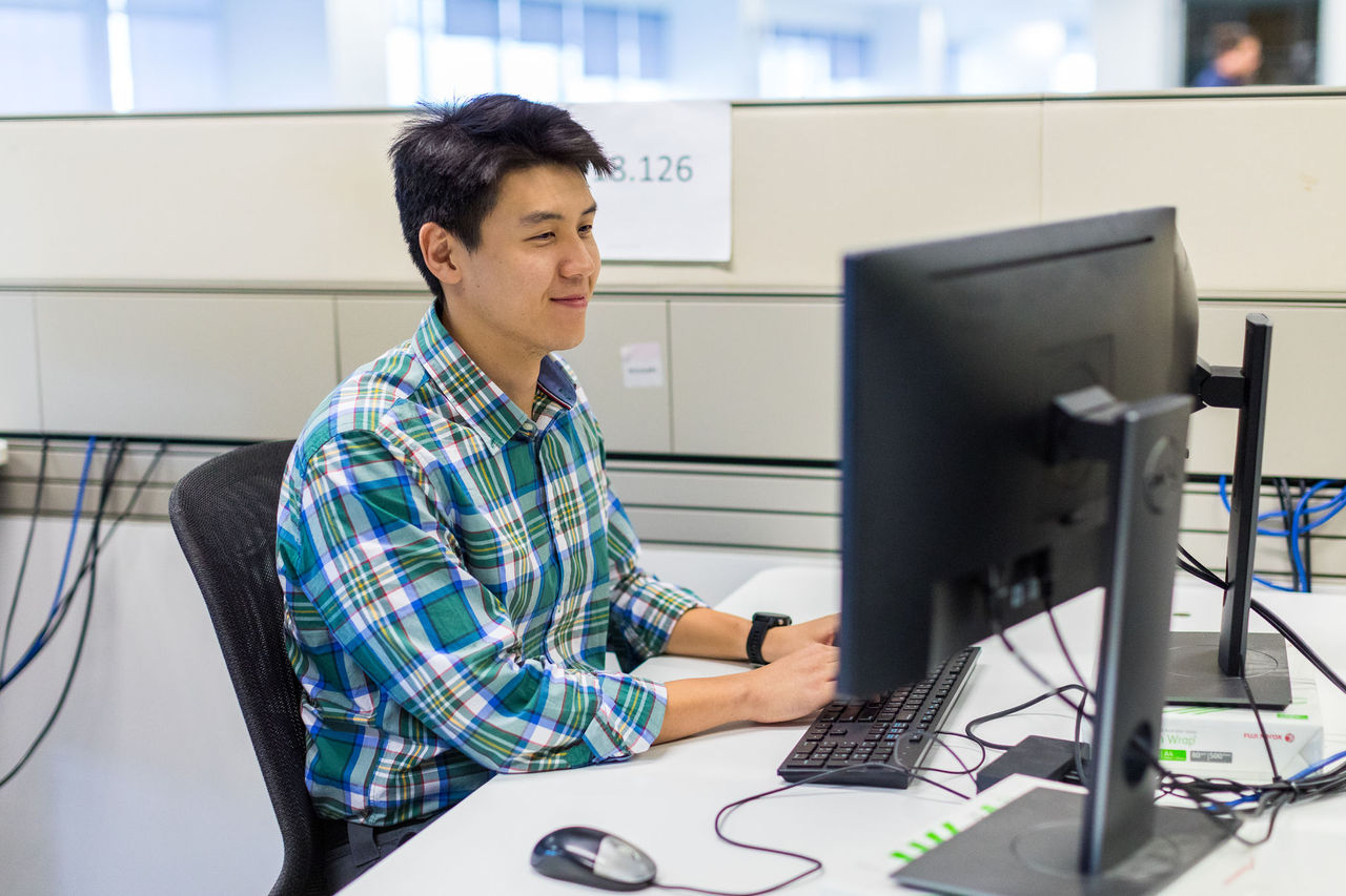 Male off-worker sitting at a work desk using a desktop computer.