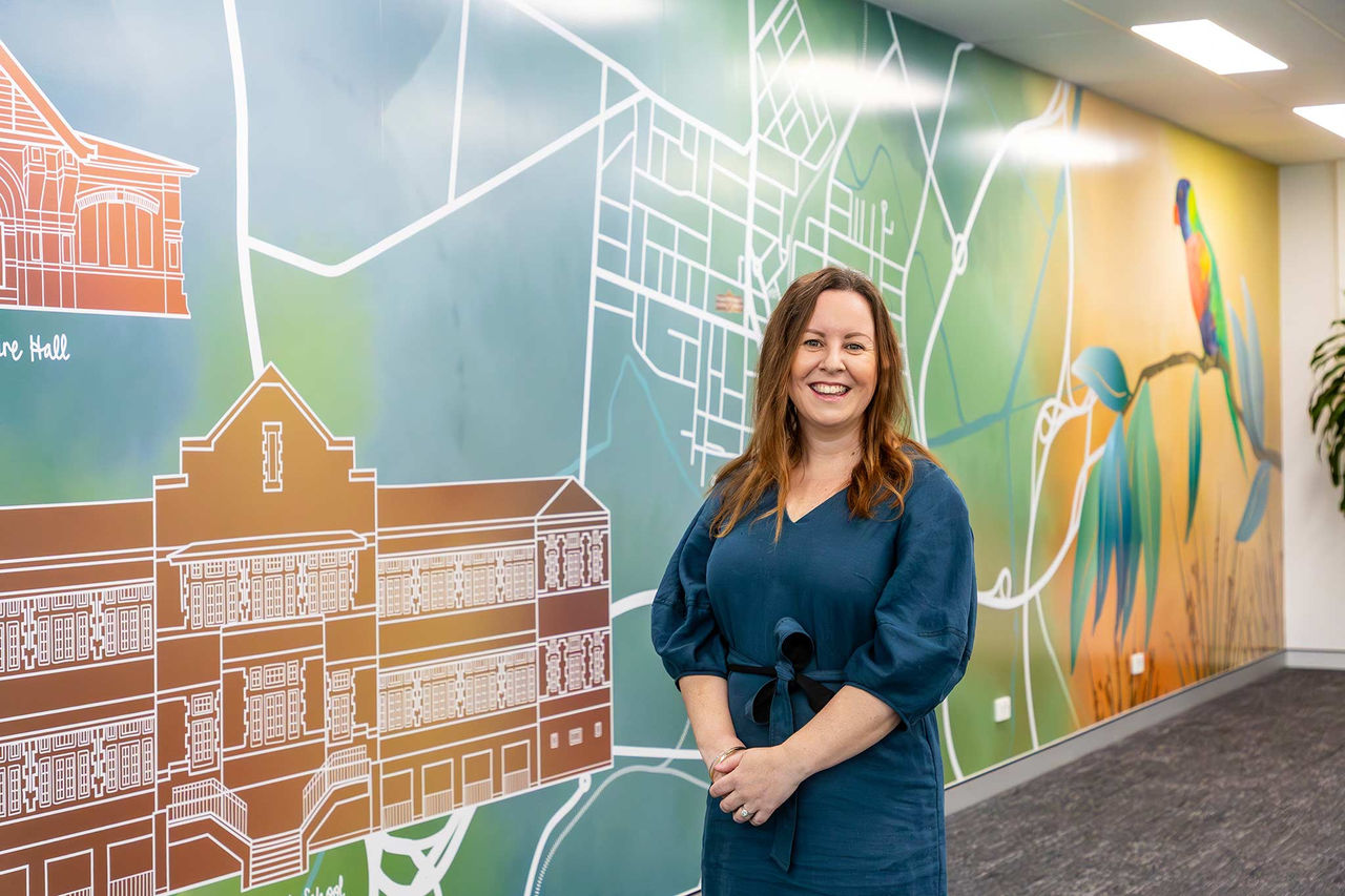 Artist in front of mural wall at Suburban Business Hub.