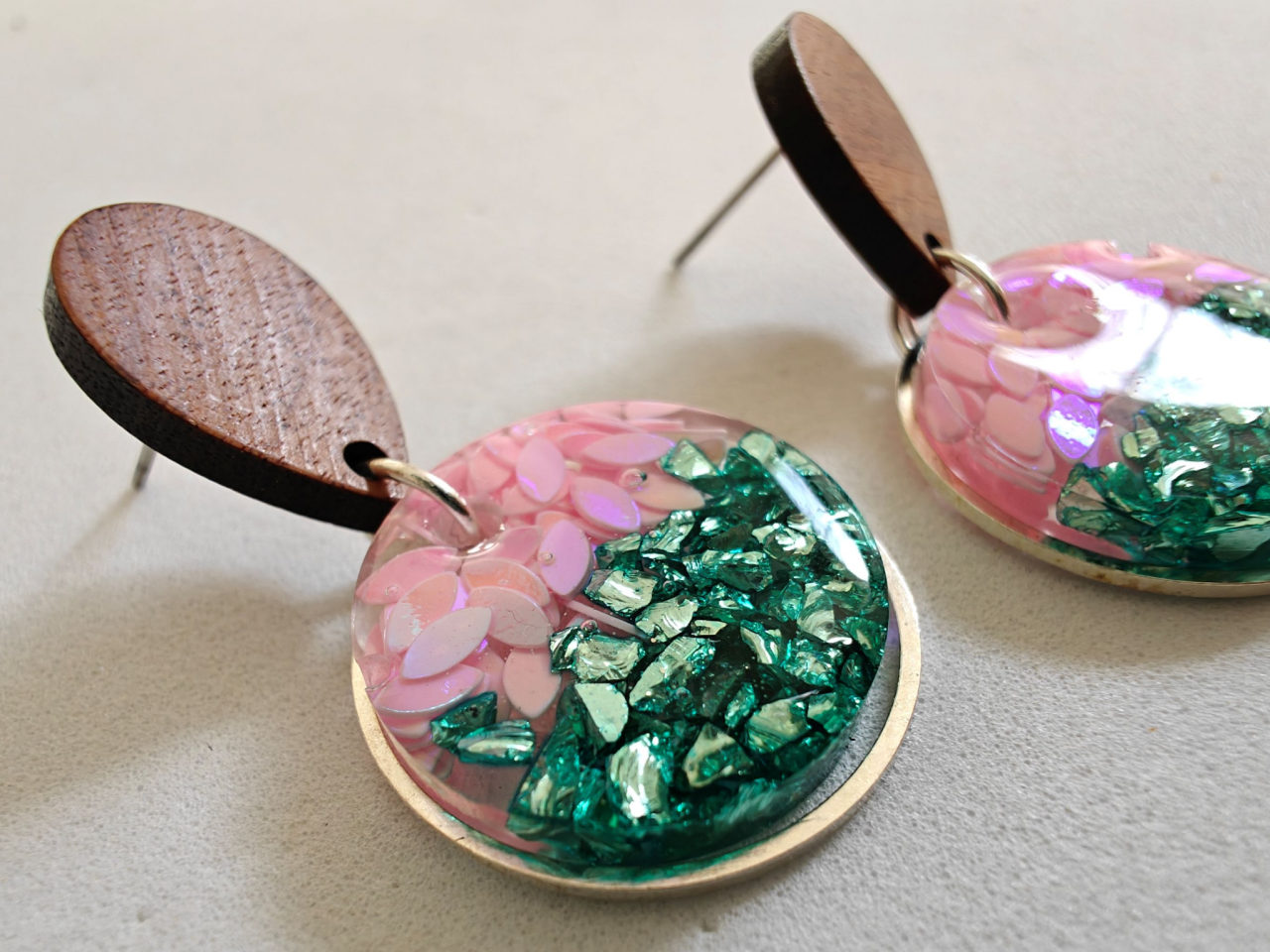 This image shows a pair of pink, green, brown and gold resin earrings.