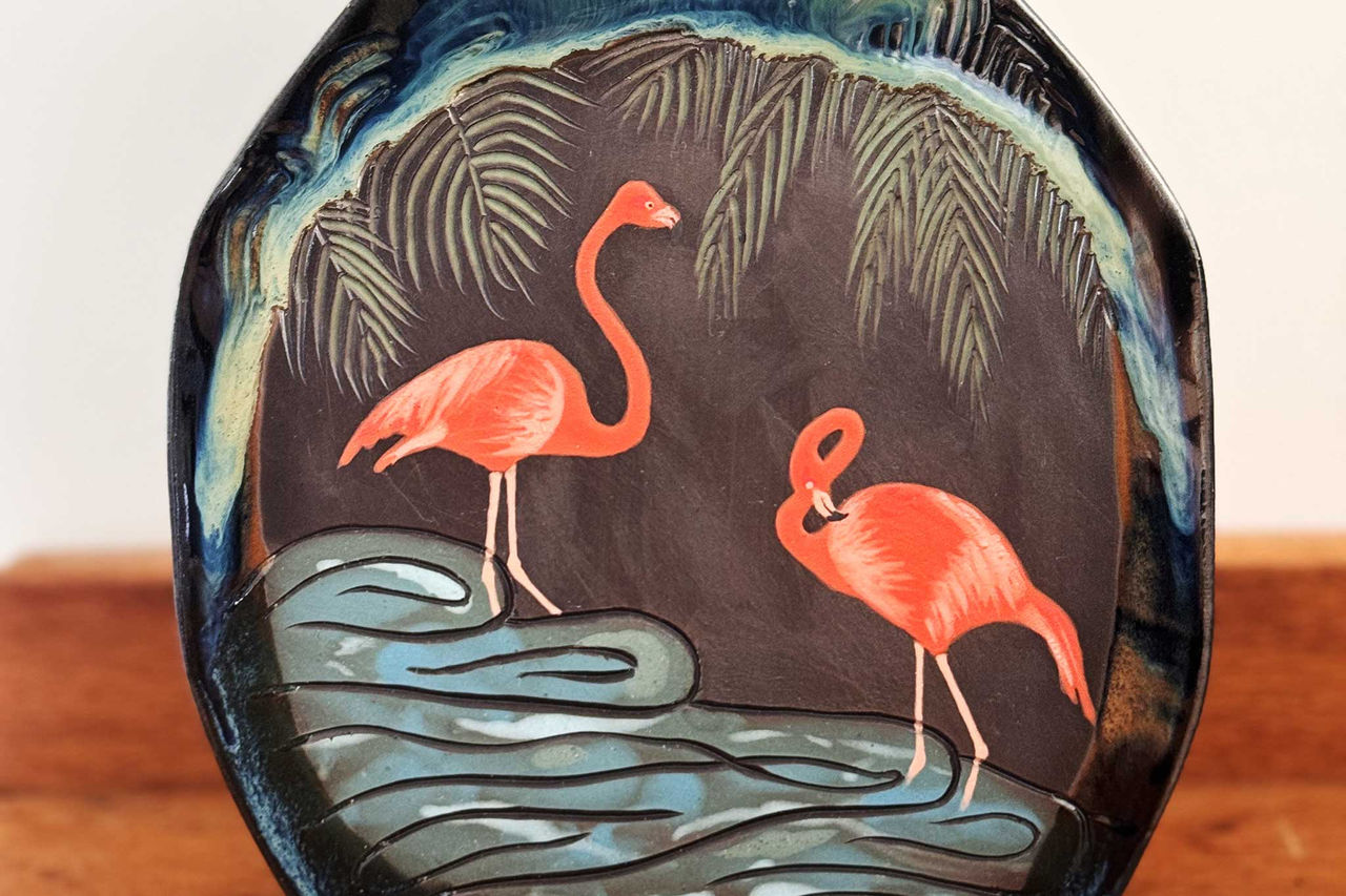 A flamingo design by Queen Sheba Ceramics on a black ceramic vase.