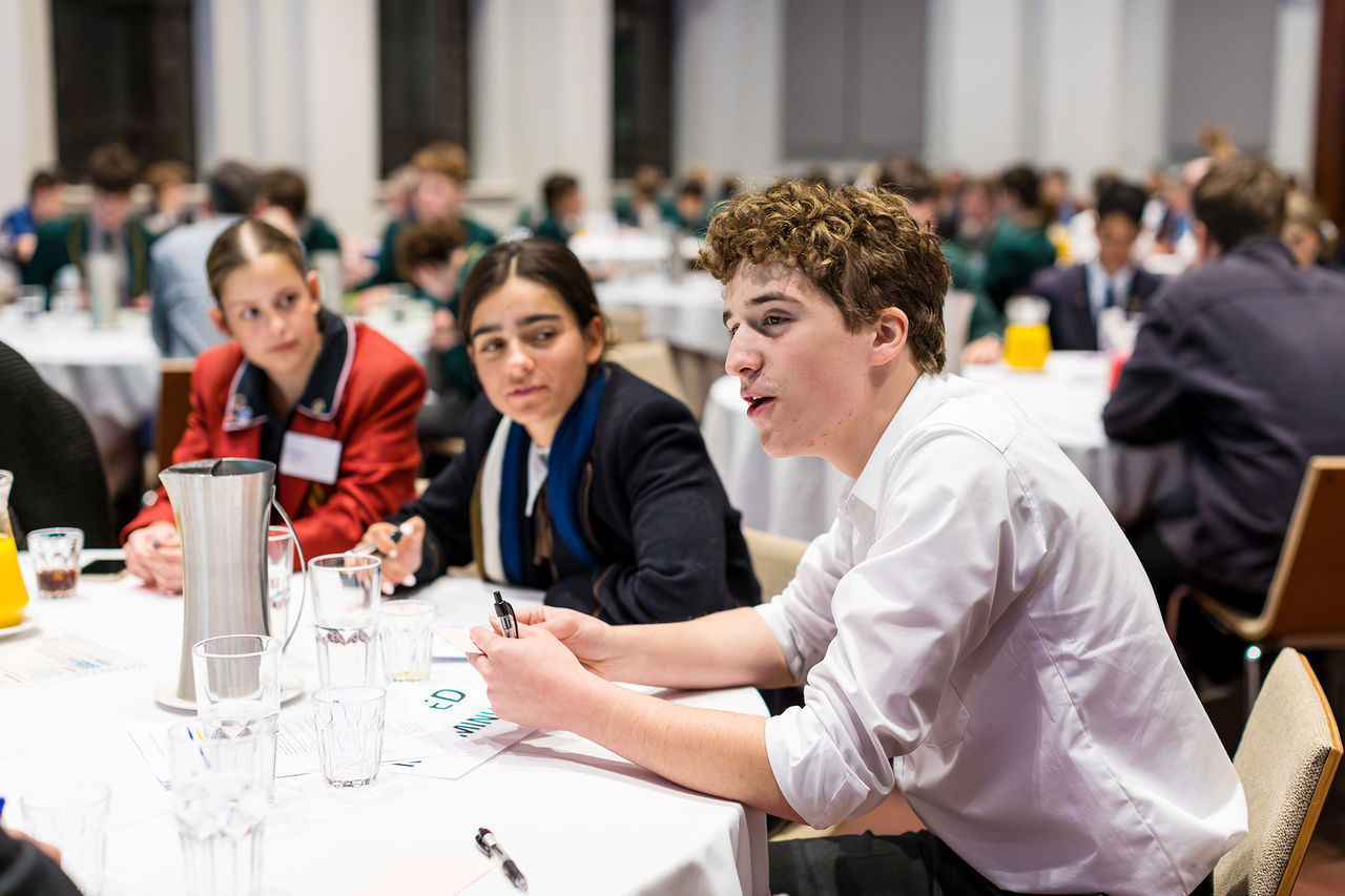 Young people collaborating around a round table at an event.