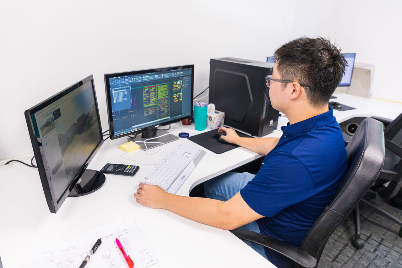 Young male professional working at a work desk with two monitors.
