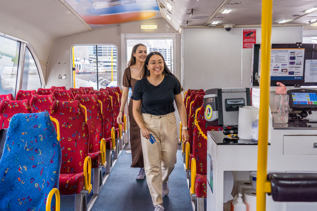 2 women walking onboard a CityCat to tap on.