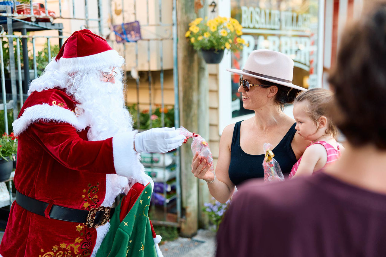 Santa handing out chocolates to Rosalie Village visitors at a First Cheer event.