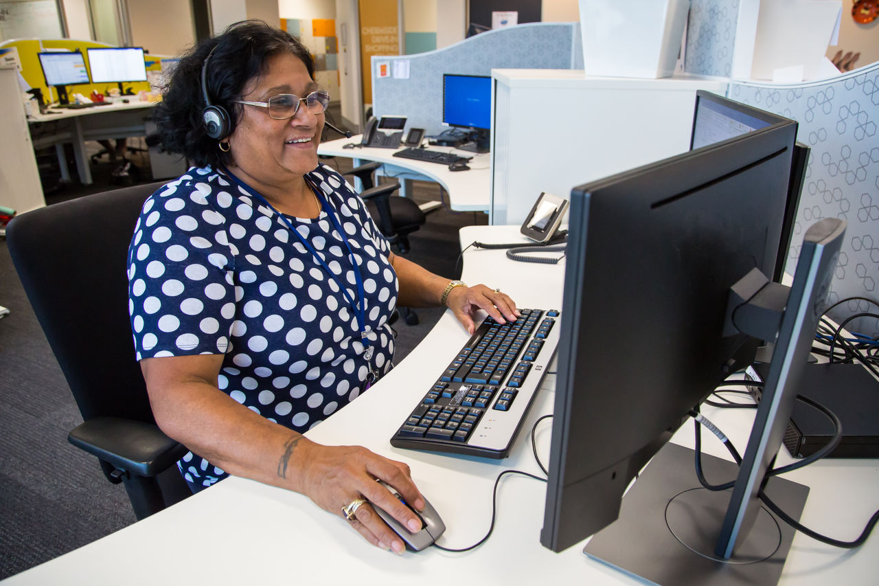 Brisbane City Council female employee sitting at a computer station with headset.