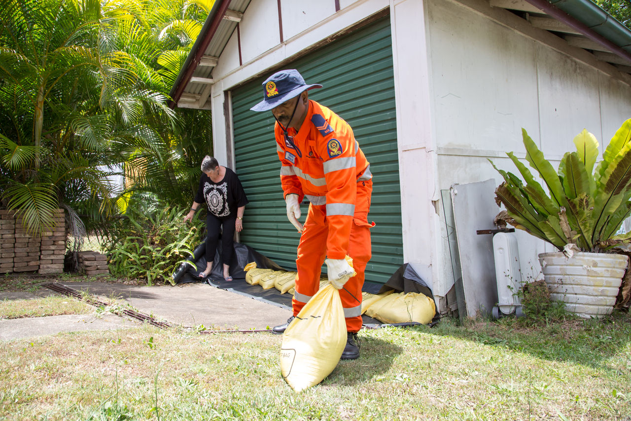 A male SES officer helping a resident sandbag her property.
