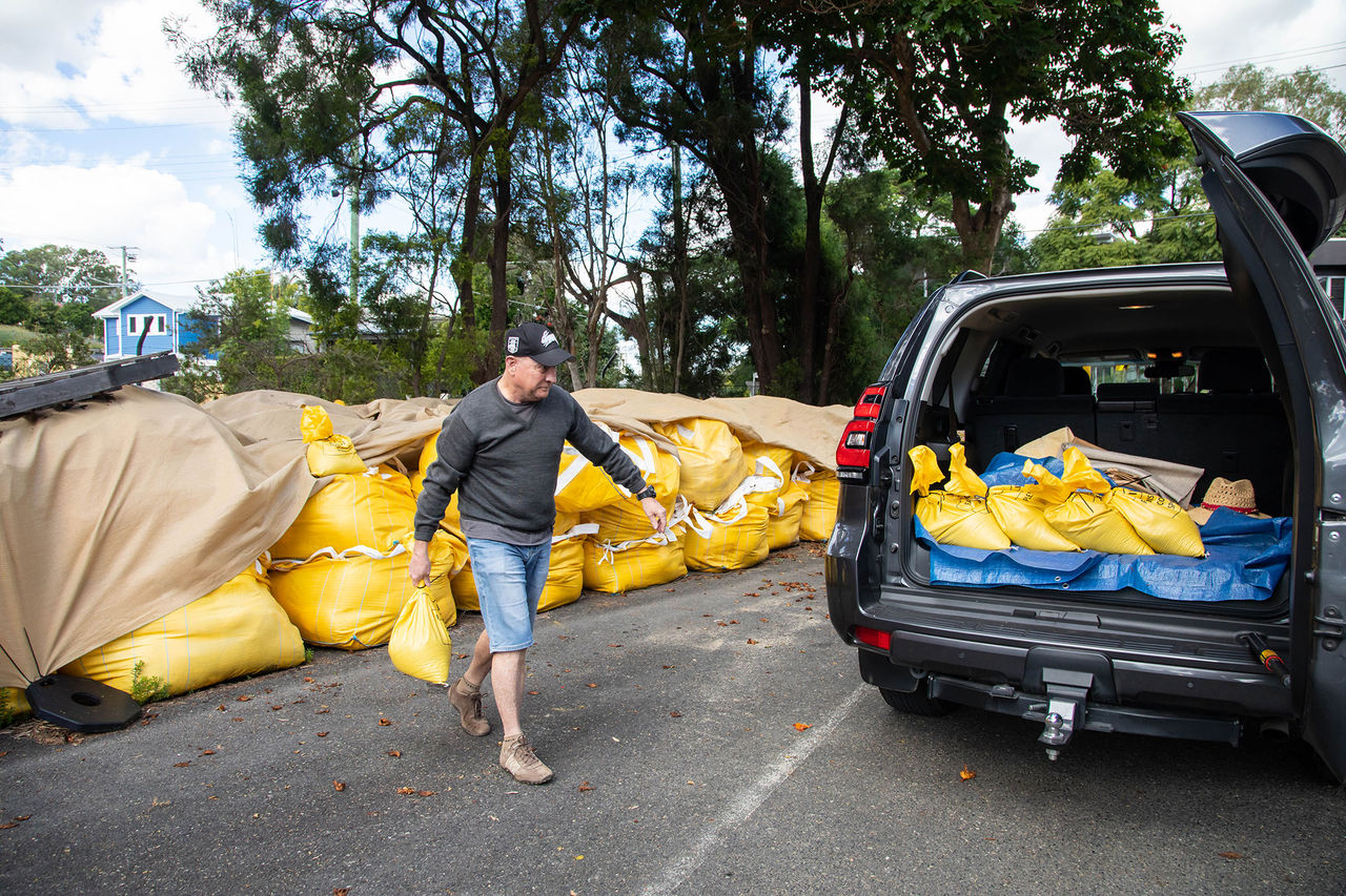 Man collecting sandbags and loading them into the back of his car.
