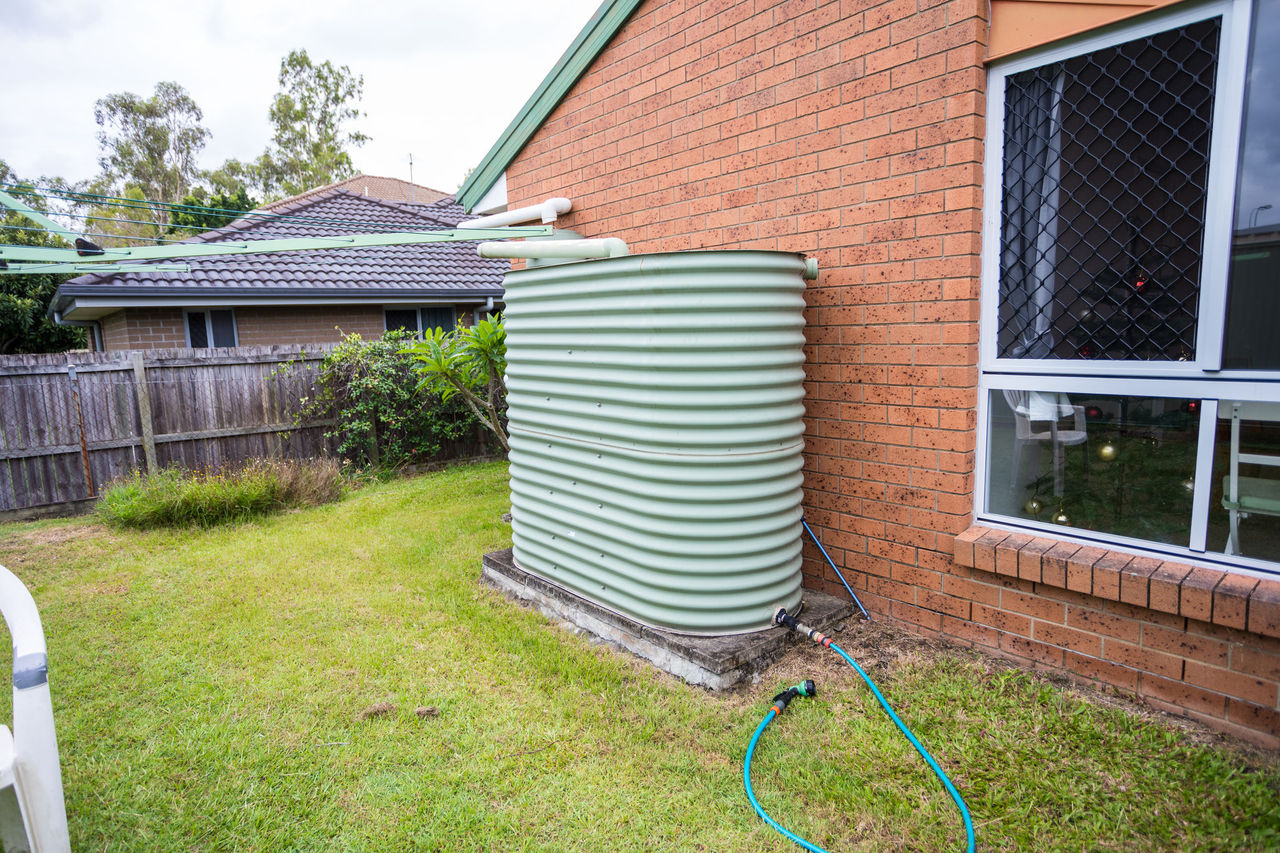 Rainwater tank in a Brisbane residential yard. with hose connected to tap.