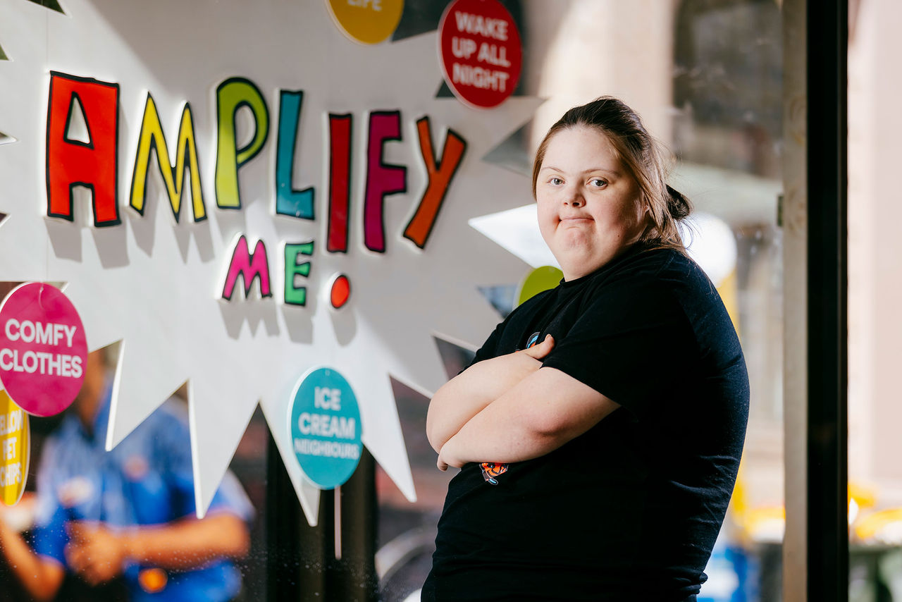 Female artist in front of Queen Street vitrine for Amplify Me! Outdoor Gallery exhibition.