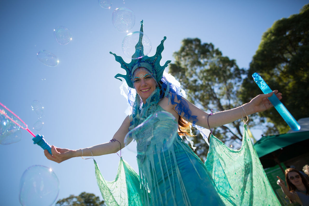 Female performer dressed in a mermaid costume blowing bubbles at Council event.