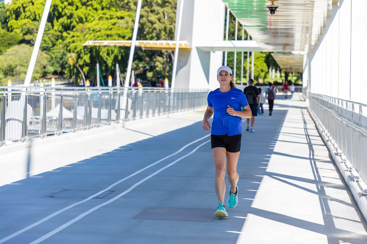 Woman in a blue shirt running across Kangaroo Point Bridge.