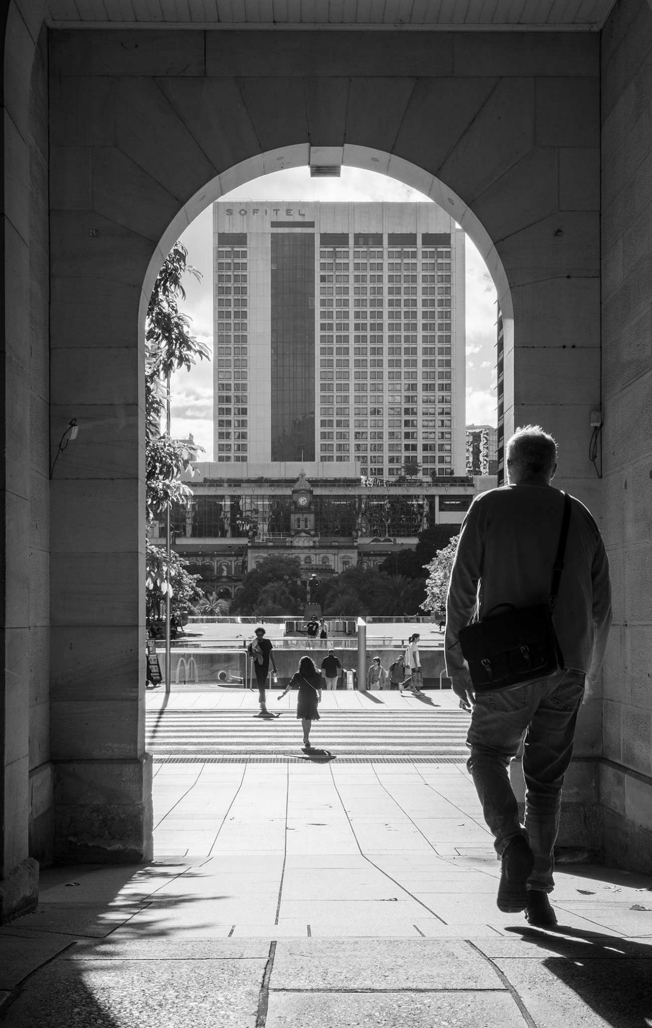 A man walking through an arch towards Post Office Square.  