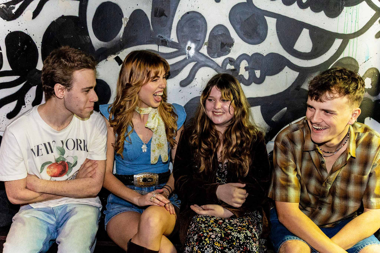 Georgia Scarlett band members - finalists in The QUBE Effect 2026 -sitting against a mural wall.
