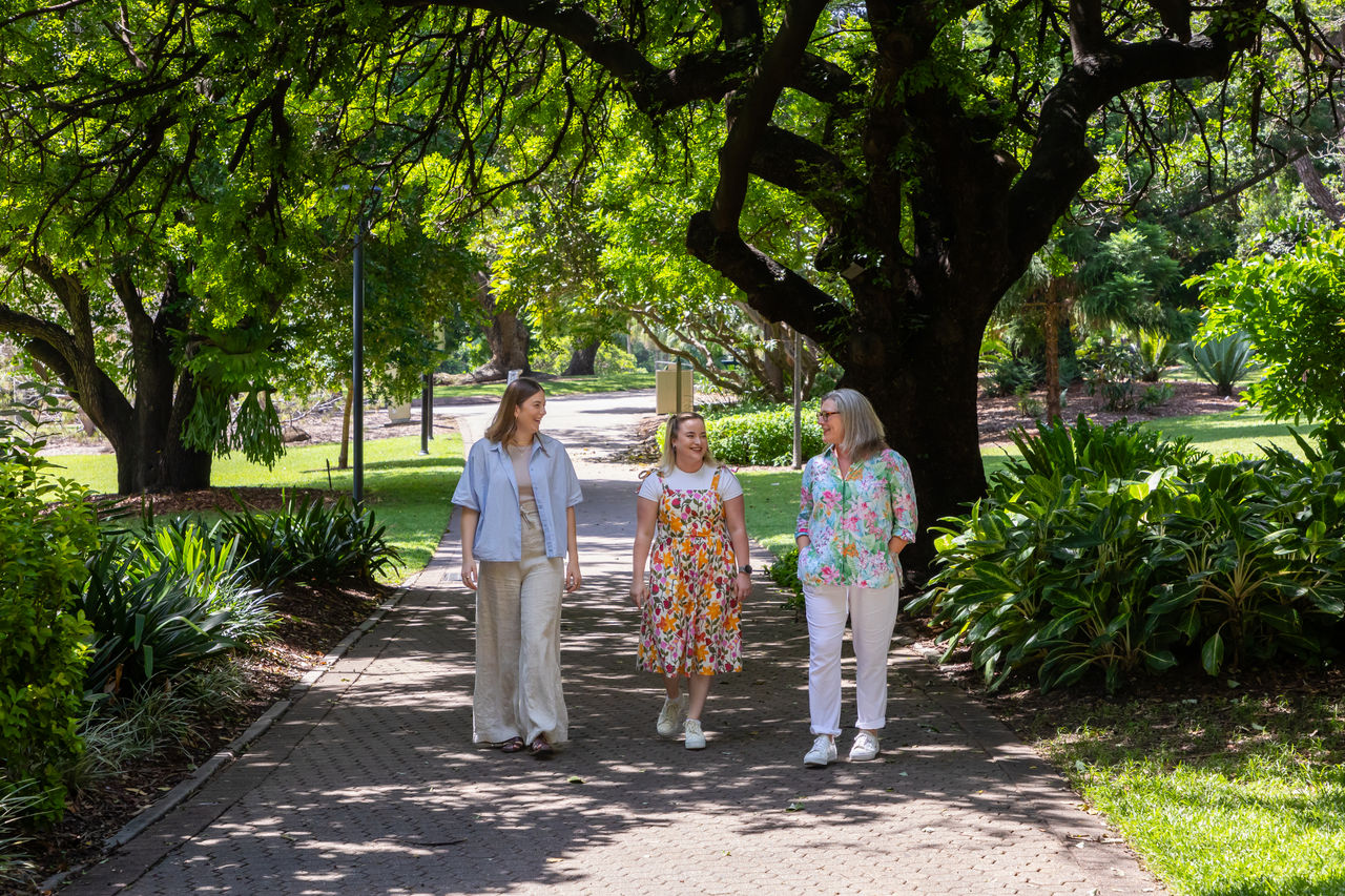 3 women walking on a shaded path through the City Botanic Gardens.