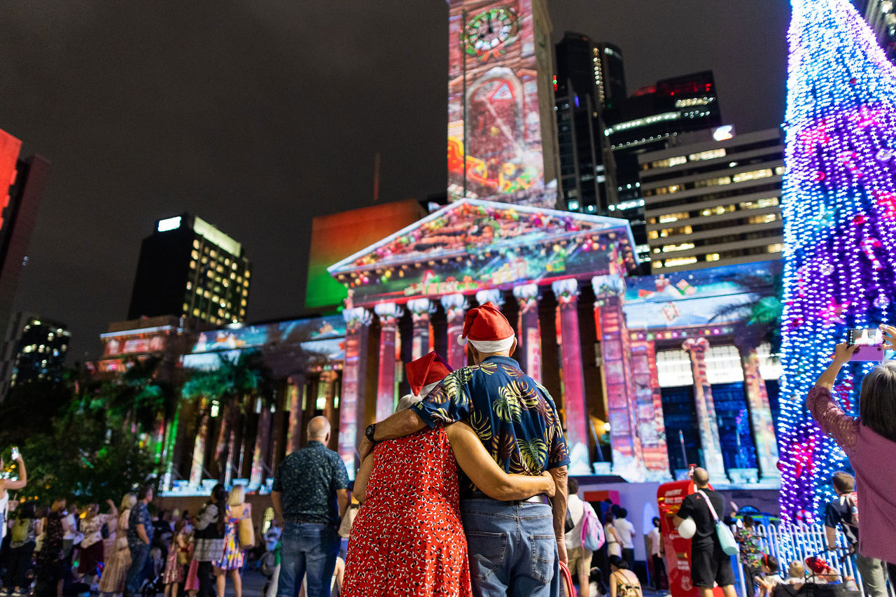 Couple at King George Square watching City Hall Lights.
