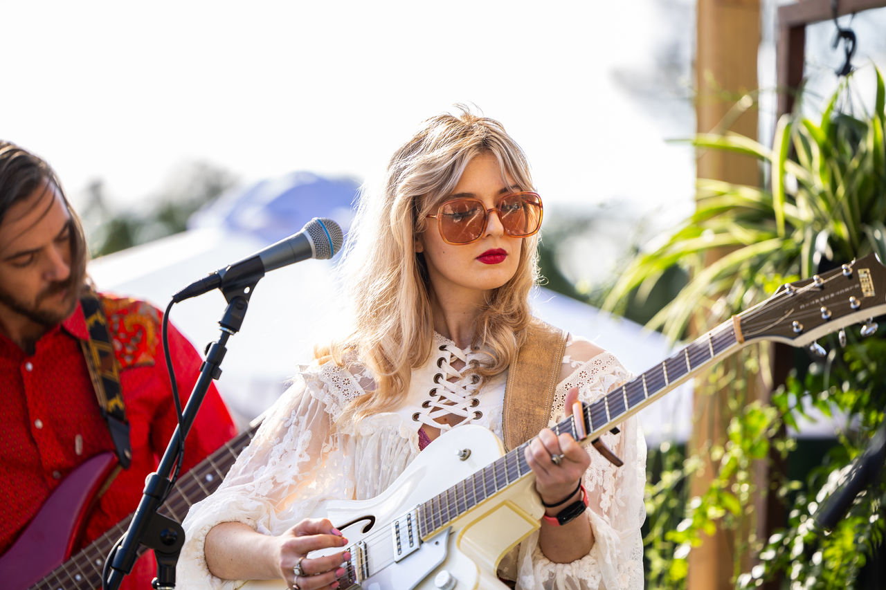 Female and male musician with guitars and mircophone on stage at a Victoria Park daytime festival..