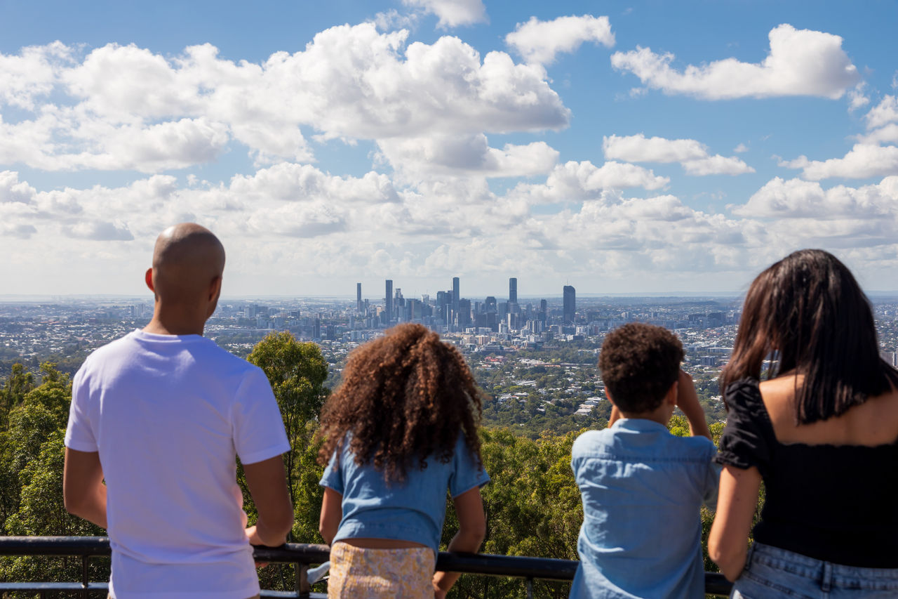 Parents with 2 children looking toward the Brisbane CBD at Mt Coot-tha Lookout.