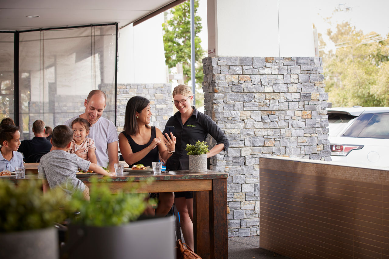 Young family seated at a table, placing an order with a waitress at Winegum Cafe