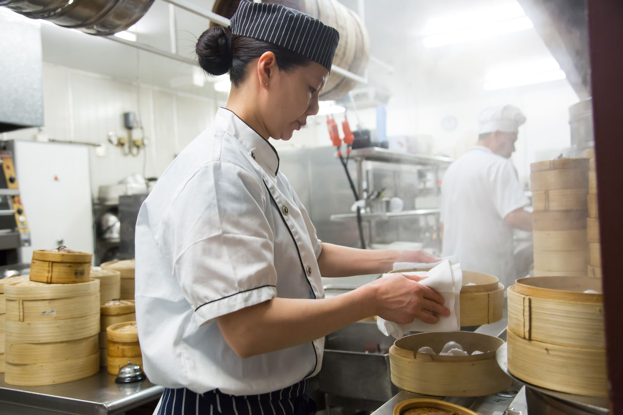 Chef working in a kitchen steaming dumplings.