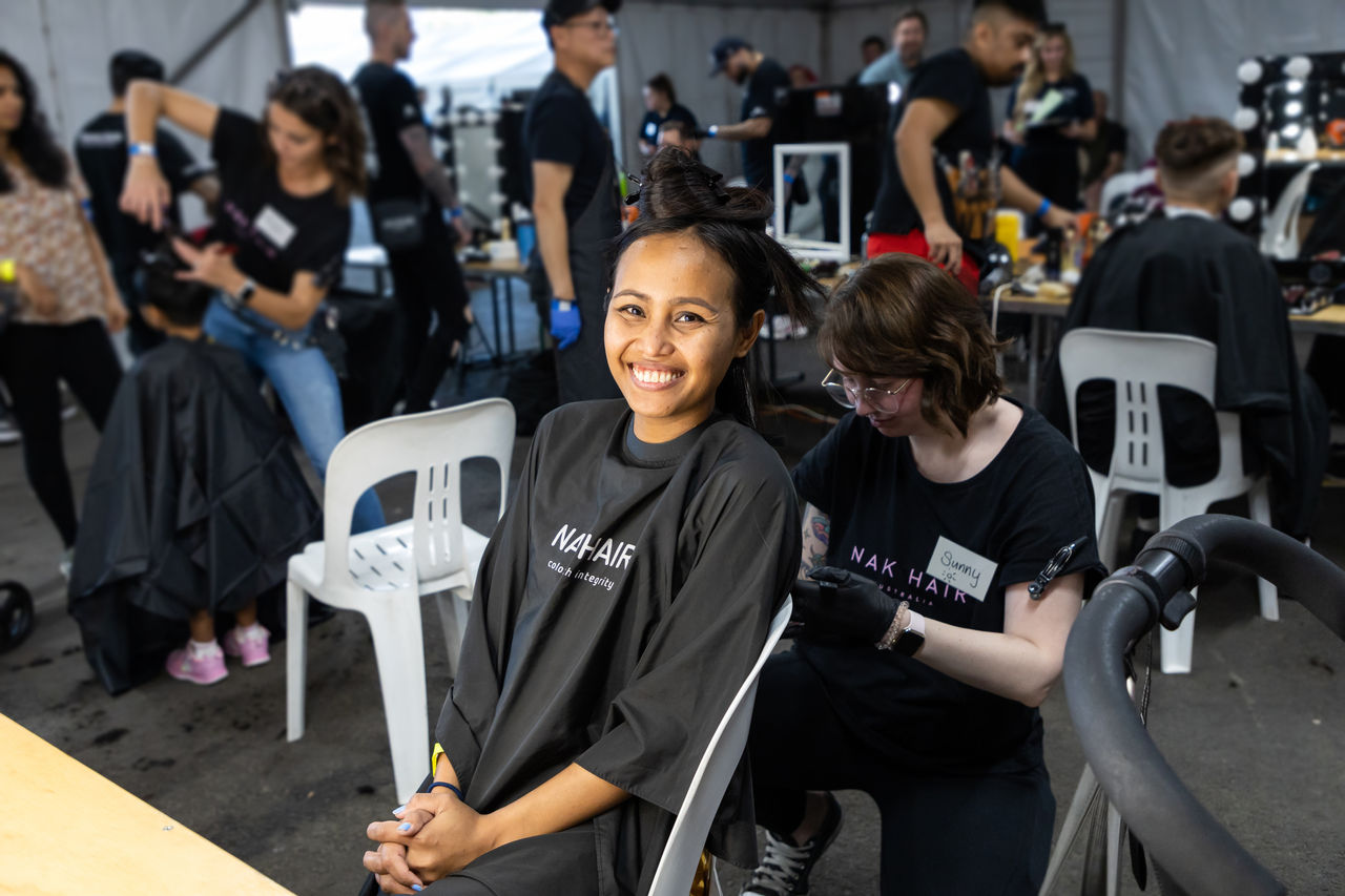 Smiling woman having her hair cut by a volunteer hairdresser at a Homeless Connect event.