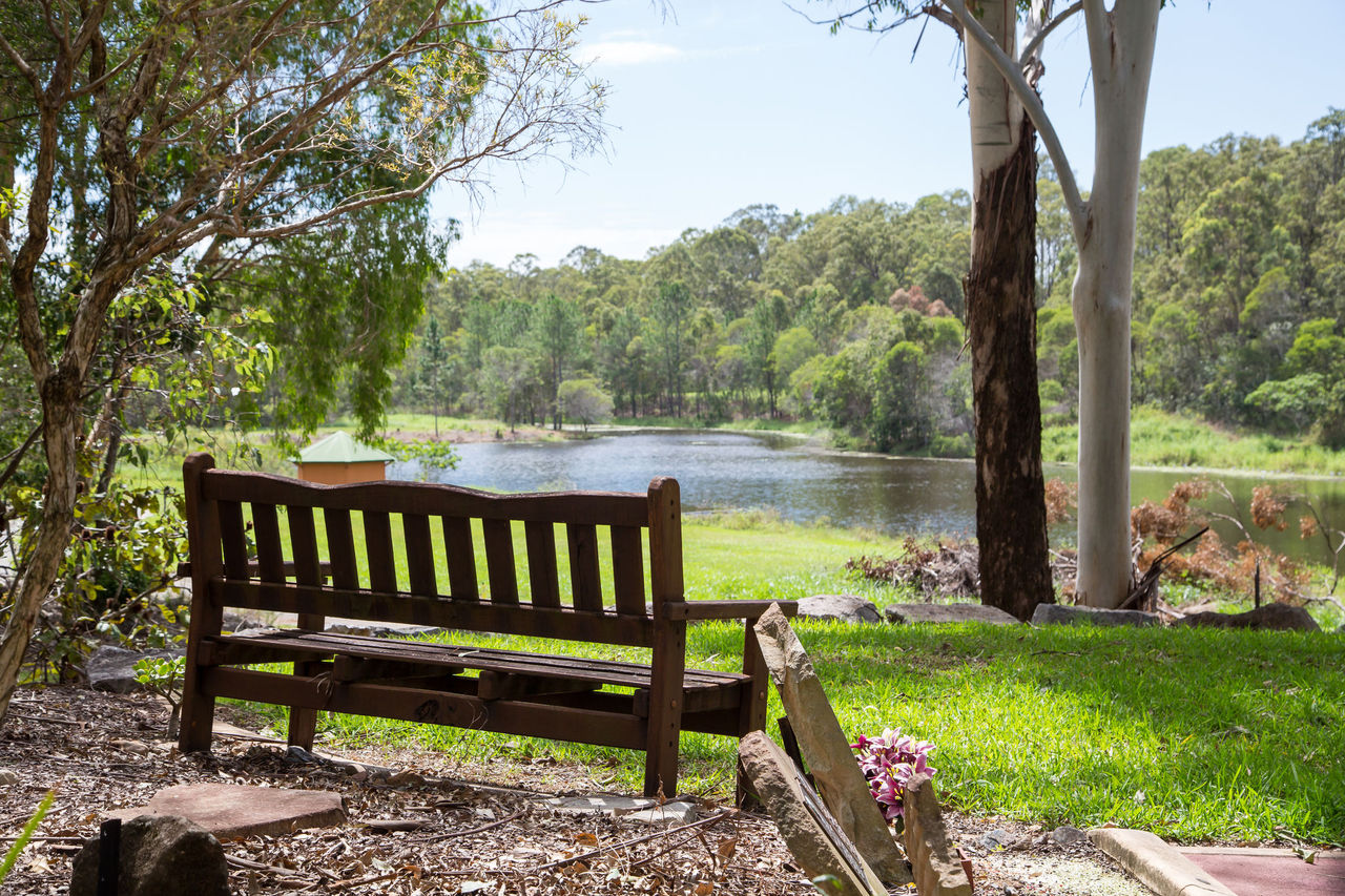 Wooden 3-seater chair overlooking water body at Pinnaroo Cemetery.