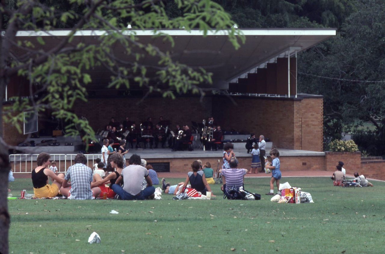 Historic colour photo showing people on grass hill watching a band concert at stage in City Botanic Gardens in 1980.