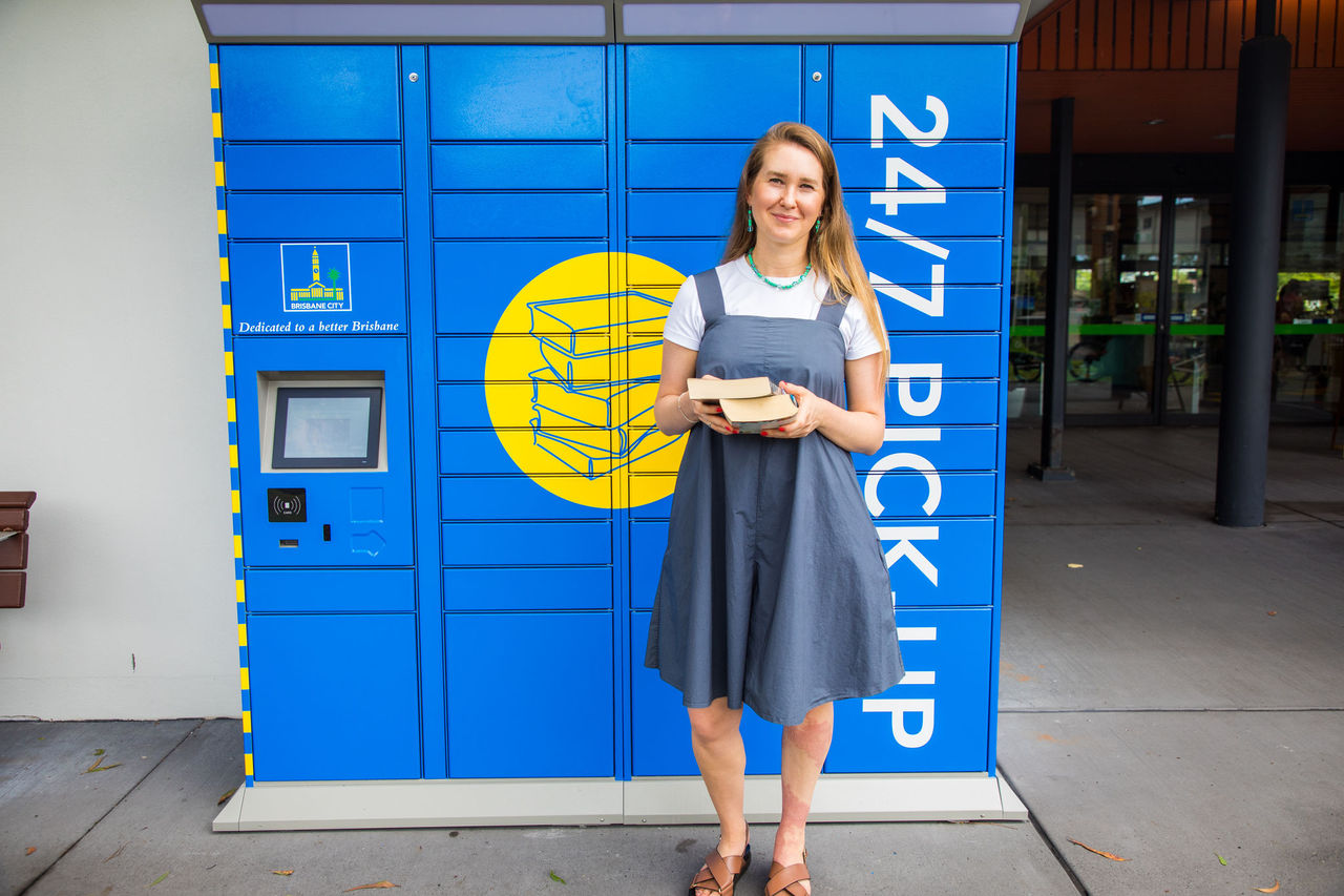 Woman collecting books from the 24/7 pickup library lockers at Mitchelton Library.
