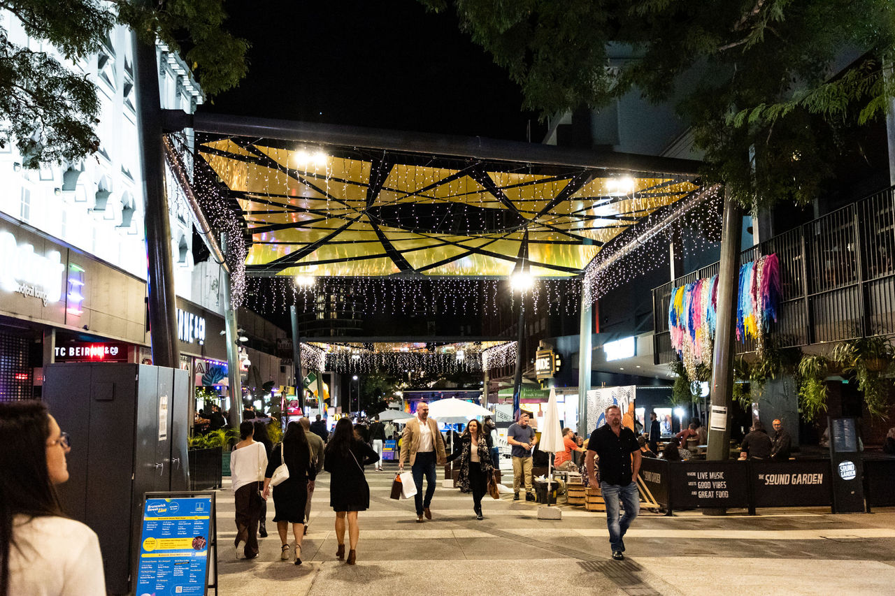 People walking through top end of Brunswick Street Mall after dark.