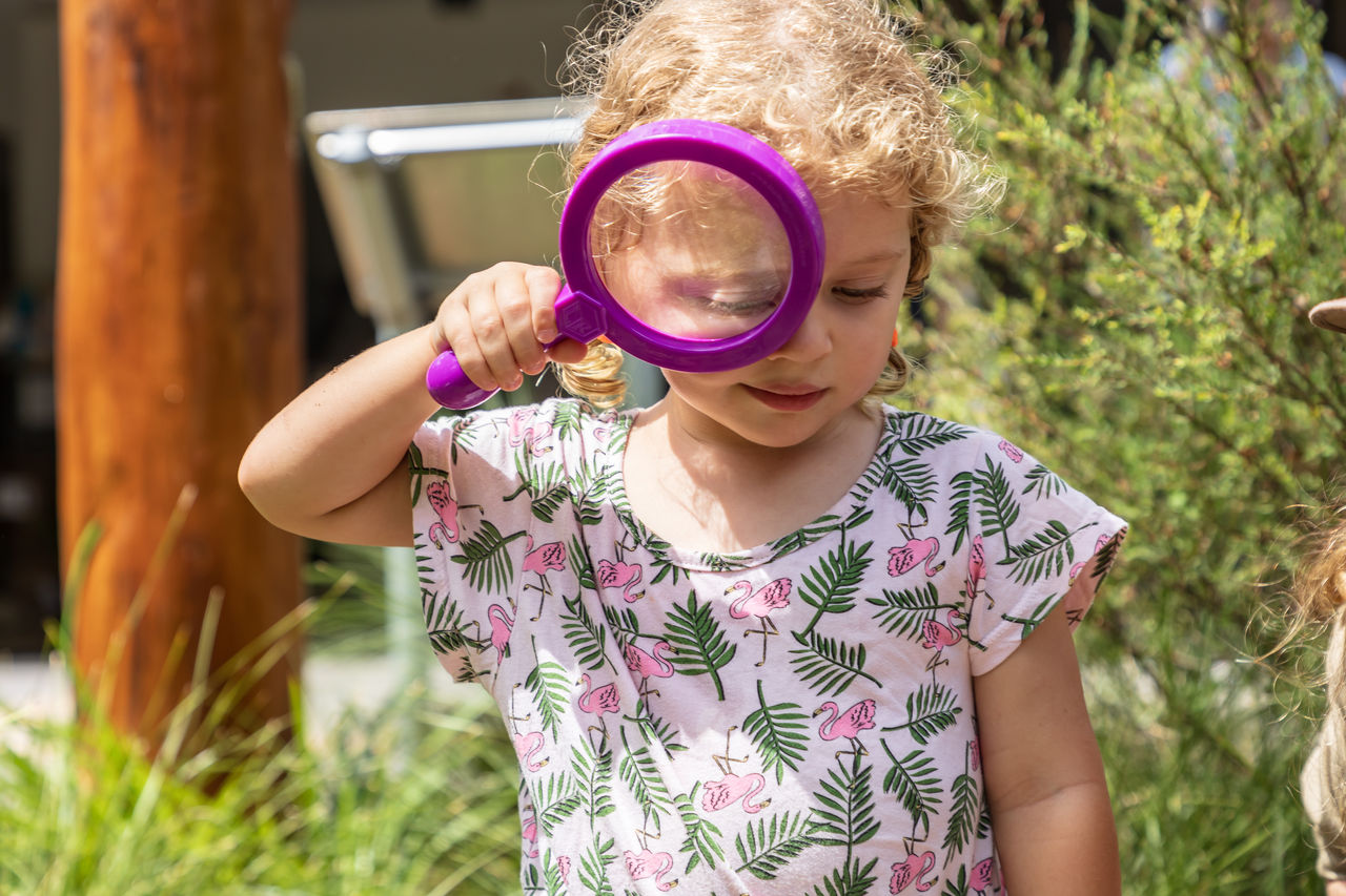 Young girl with a purple magnifying glass in the Karawatha Forest Discovery Centre grounds.
